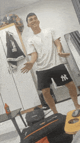 a man wearing ny shorts and a white shirt stands in a room