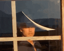 a man is looking out of a window with a piece of paper flying in the air