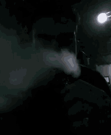 a person smoking a cigarette in a dark room with smoke coming out of their mouth