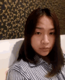 a woman wearing a striped shirt is sitting on a couch and making a funny face .