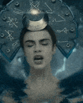 a woman with her eyes closed has a crown on her head with the letter x on it