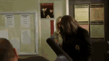a group of people are standing in front of a bulletin board with a picture of macbeth on it .