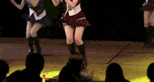 a girl in a plaid skirt is dancing on stage