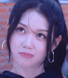 a close up of a woman 's face with hoop earrings and a ponytail .