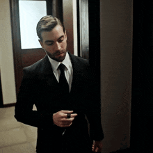 a man in a suit and tie holds a ring in his hand