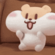 a stuffed animal is sitting on a couch with its tongue hanging out .