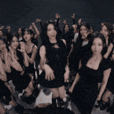 a group of women in black dresses are dancing