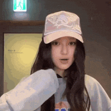 a woman wearing a baseball cap and a sweatshirt is standing in front of a door .
