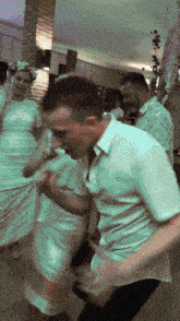 a man in a white shirt dancing with a woman in a white dress behind him