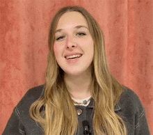 a woman with long blonde hair is smiling and wearing a necklace