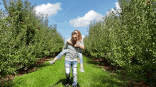 a man is carrying a woman on his back through a field of apple trees