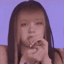 a woman with long hair is making a funny face while holding her hands to her mouth .