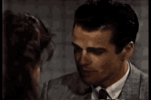 a man in a suit and tie is kissing a woman in a movie .