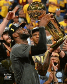 a man is holding a basketball trophy in his hands in front of a crowd .