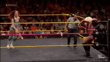 two women are wrestling in a ring while a referee watches