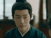 a man with a bun on his head and a blue shirt