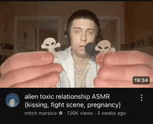 a man wearing headphones is holding two skulls in his hands while talking into a microphone .