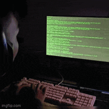 a person is typing on a keyboard in front of a computer monitor with a green screen
