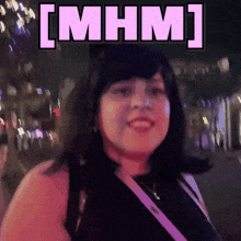 a woman is smiling in front of a sign that says [ mhm ] on it