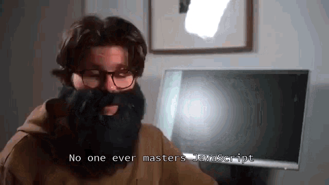a man with glasses and a fake beard says no one ever masters javascript .