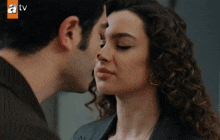 a man kisses a woman on the forehead in front of a tv screen