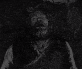 a man with a beard is tied to a rope with his eyes closed