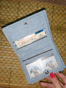 a person holding a wallet with a foreign license in it