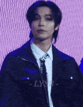a man wearing a black jacket and tie with lysb written on the bottom right