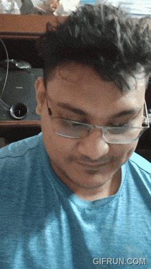 a man wearing glasses and a blue shirt has a gifrun.com watermark