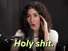 a woman speaking into a microphone with the words holy shit on the screen