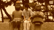 a man is sitting on a ledge between two statues of people .
