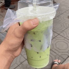 a person is holding a cup of green liquid