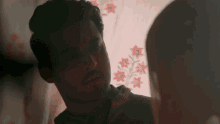 a man with a beard is looking at a woman with red flowers on her shirt