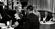 a black and white photo of a man and a woman dancing in a room .