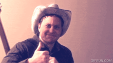 a man in a cowboy hat giving a thumbs up