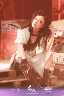 a woman in a white dress and black boots sits in front of a car with the number 317