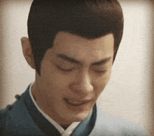 a close up of a man 's face with his eyes closed and a blue jacket on