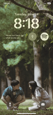 a phone screen shows a man and a woman kneeling in the grass on tuesday june 24