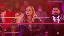 a woman in a blue dress is standing in a wrestling ring with a referee