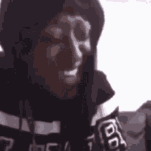 a close up of a person wearing a hoodie and a scarf talking into a microphone .