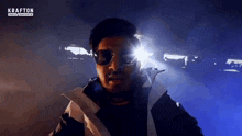 a man wearing sunglasses is standing in front of a krafton india esports logo