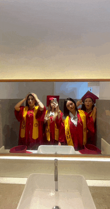 a group of female graduates pose for a picture in front of a mirror