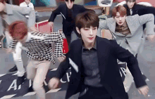 a group of young men in suits are dancing on a stage .