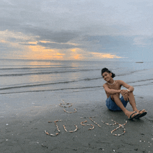 a young man sits on the beach with the word justy written in the sand