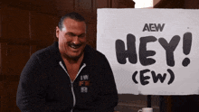 a man is laughing in front of a sign that says hey ( ew )