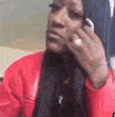 a woman is talking on a cell phone while wearing a red jacket .