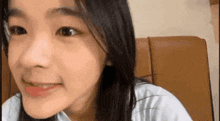 a young girl is smiling and looking at the camera while sitting on a chair .