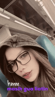 a girl wearing glasses and a hoodie says hmm