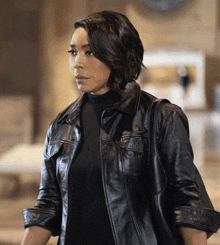 a woman is wearing a black leather jacket and a black shirt .