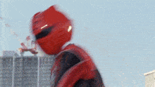 a man in a red superhero costume is standing in front of a building under construction .
